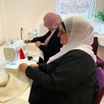 Kvinnor sitter vid symaskiner och arbetar.