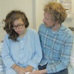Kvinna och en man sitter på en säng på sjukhus